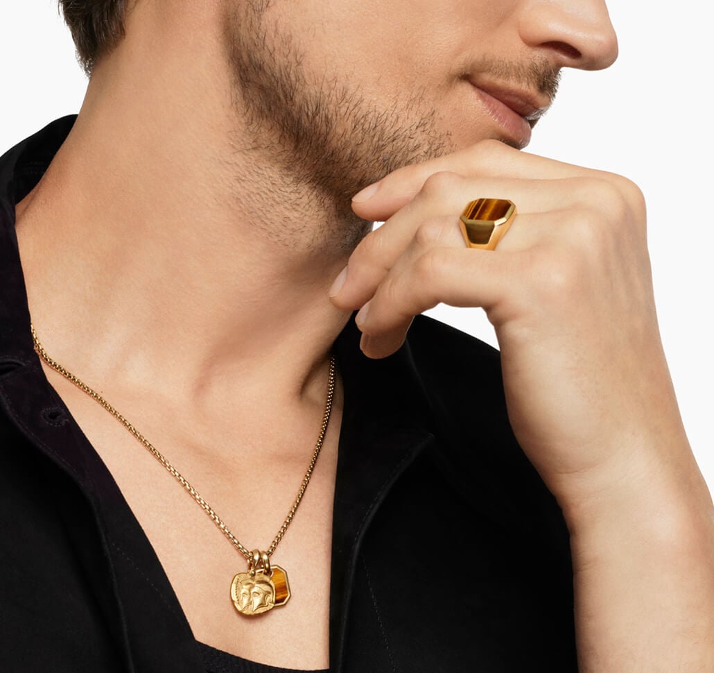 A man wearing David Yurman pendants on a necklace.