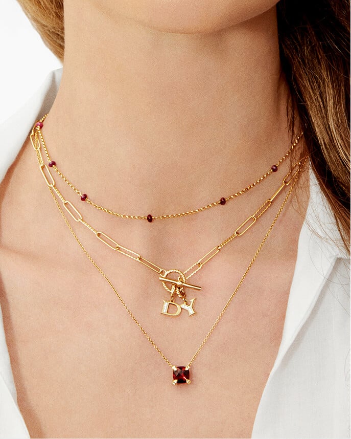 A woman layering three David Yurman necklaces with charms.