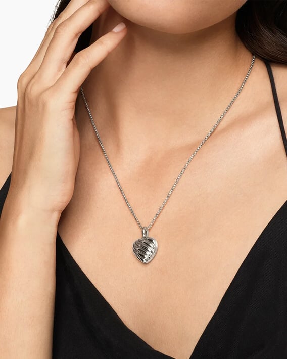 A woman wearing a silver David Yurman amulet.