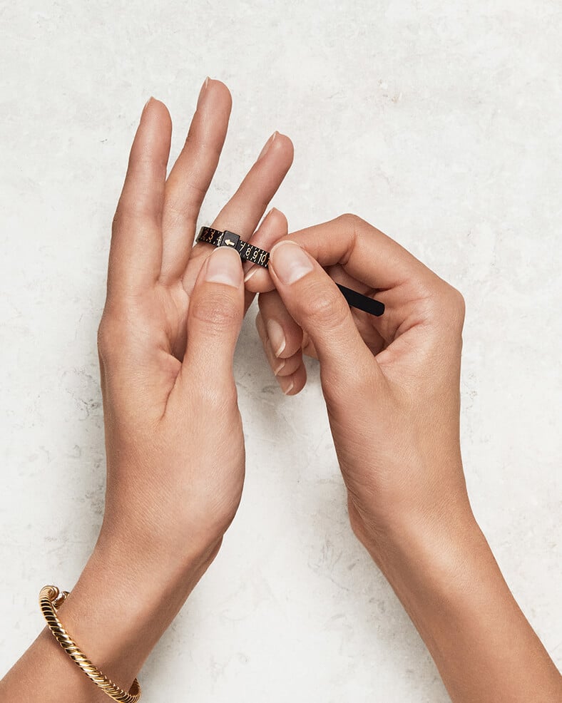 Hands holding a David Yurman ring sizer.