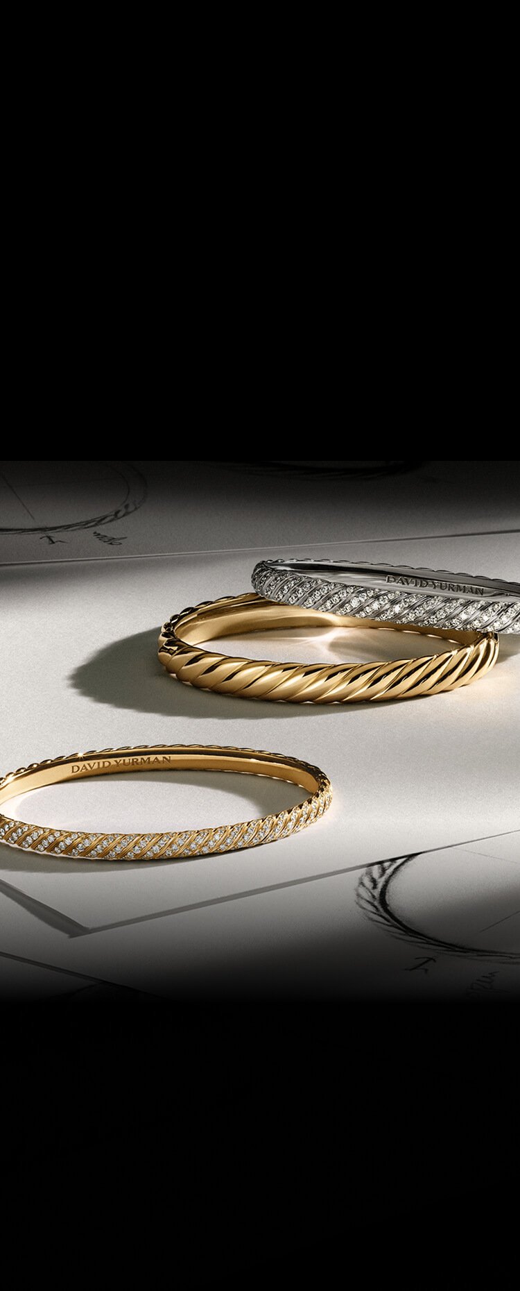 Three David Yurman Sculpted Cable bangles on paper.